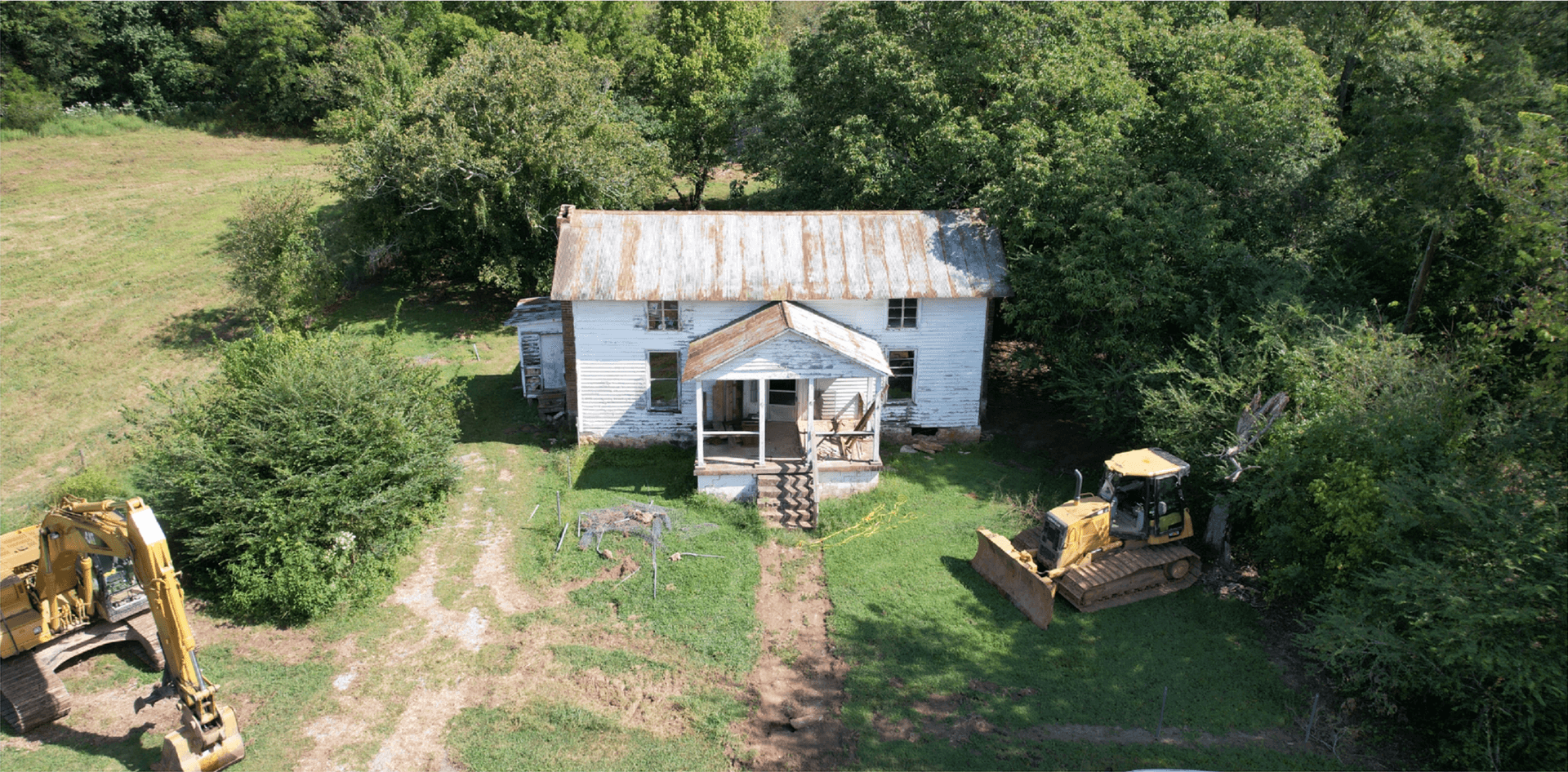 Demolition site with equipment near a farmhouse