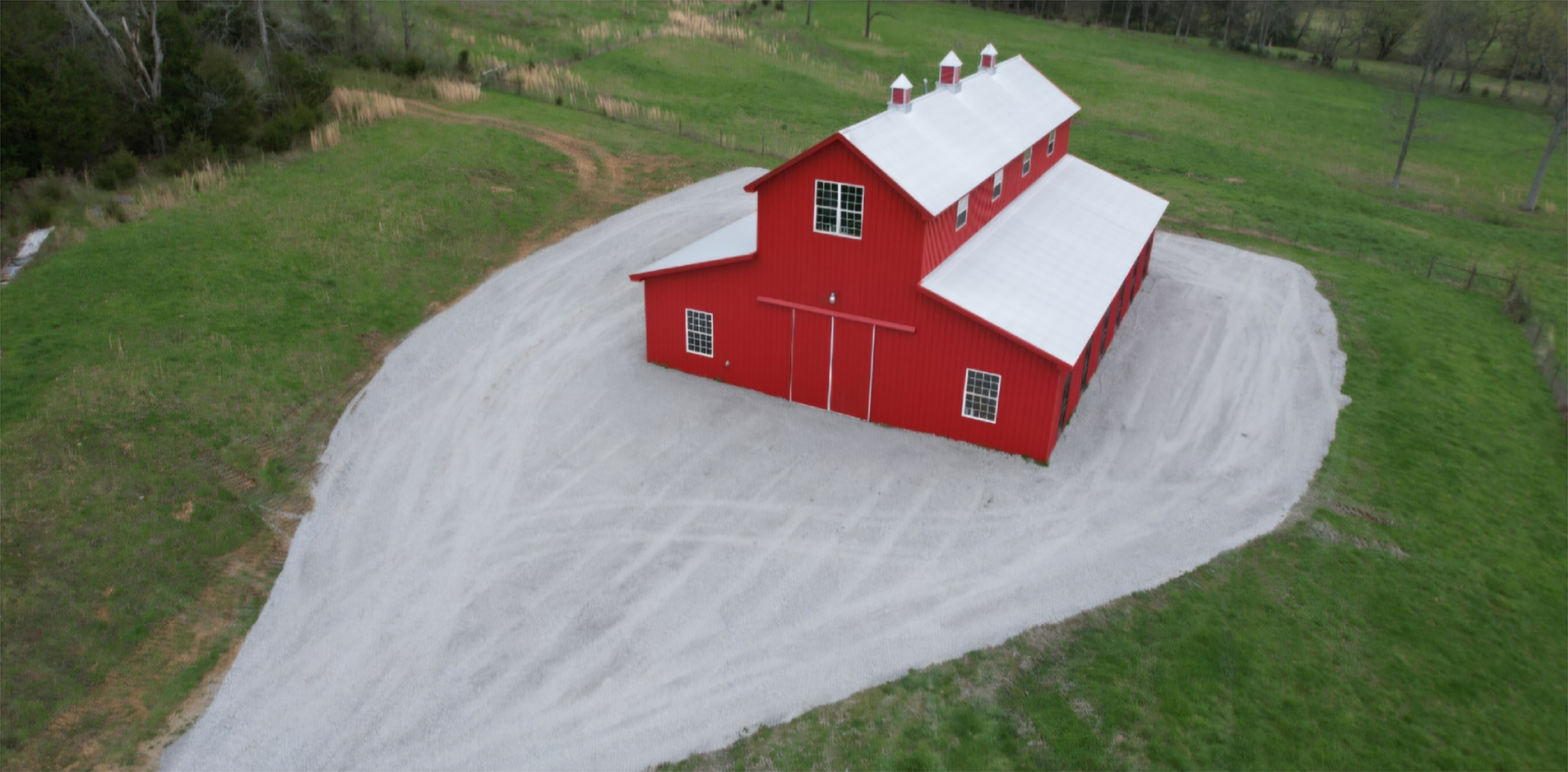 Aerial view of a red barn with a fresh gravel pad